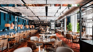A restaurant with multiple dining areas, tables set with wine glasses and plates, and a variety of seating options. - QT Perth (Perth)