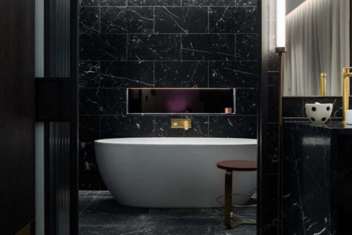 A modern bathroom with a freestanding bathtub, a vanity with a mirror, and a small stool.