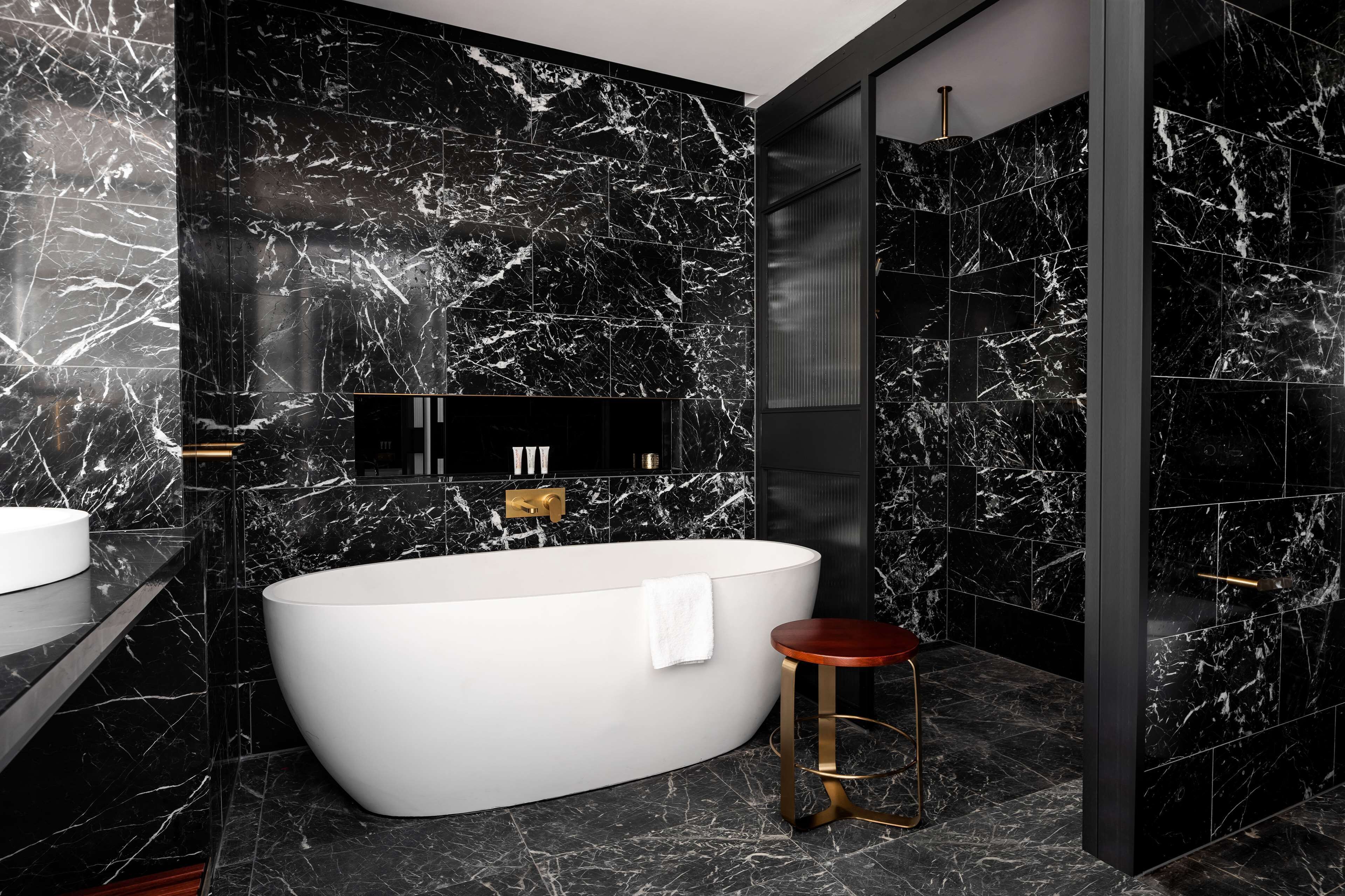 Un baño moderno con una bañera independiente, un tocador con lavamanos y un taburete.