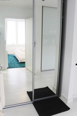 A modern bedroom with a glass door leading to a bathroom, a blue carpet, and a black doormat. - Golden Sun Apartments  - Grzybowo (Kolobrzeg)
