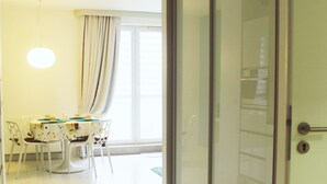 A room with a dining area featuring a table and chairs, a sliding glass door, and a light fixture. - Golden Sun Apartments  - Grzybowo (Kolobrzeg)
