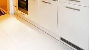 A modern kitchen with white cabinets, a stainless steel oven, and a sink. - Golden Sun Apartments  - Grzybowo (Kolobrzeg)