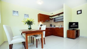 Una cocina moderna con armarios de madera, una mesa de comedor con sillas, un jarrón de flores y un televisor sobre un mueble de madera.