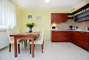 A modern kitchen with wooden cabinets, a dining table with chairs, and a vase of flowers.