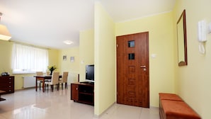 Habitación de hotel con zona de comedor, televisor, puerta de madera y teléfono.