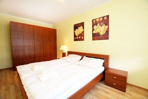 A bedroom with a wooden bed, a nightstand, a wardrobe, and two floral paintings on the wall.