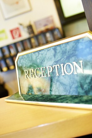 A reception desk with a marble top and the word "RECEPTION" prominently displayed. - Haus Niemann (Münster)