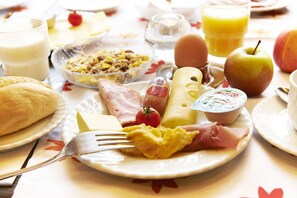 A breakfast table with various food items including eggs, toast, cheese, and fruit. - Haus Niemann (Münster)