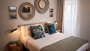 A neatly arranged bedroom with a bed, bedside lamps, and decorative mirrors on the wall. - Hotel Cruzeiro (Angra do Heroismo)