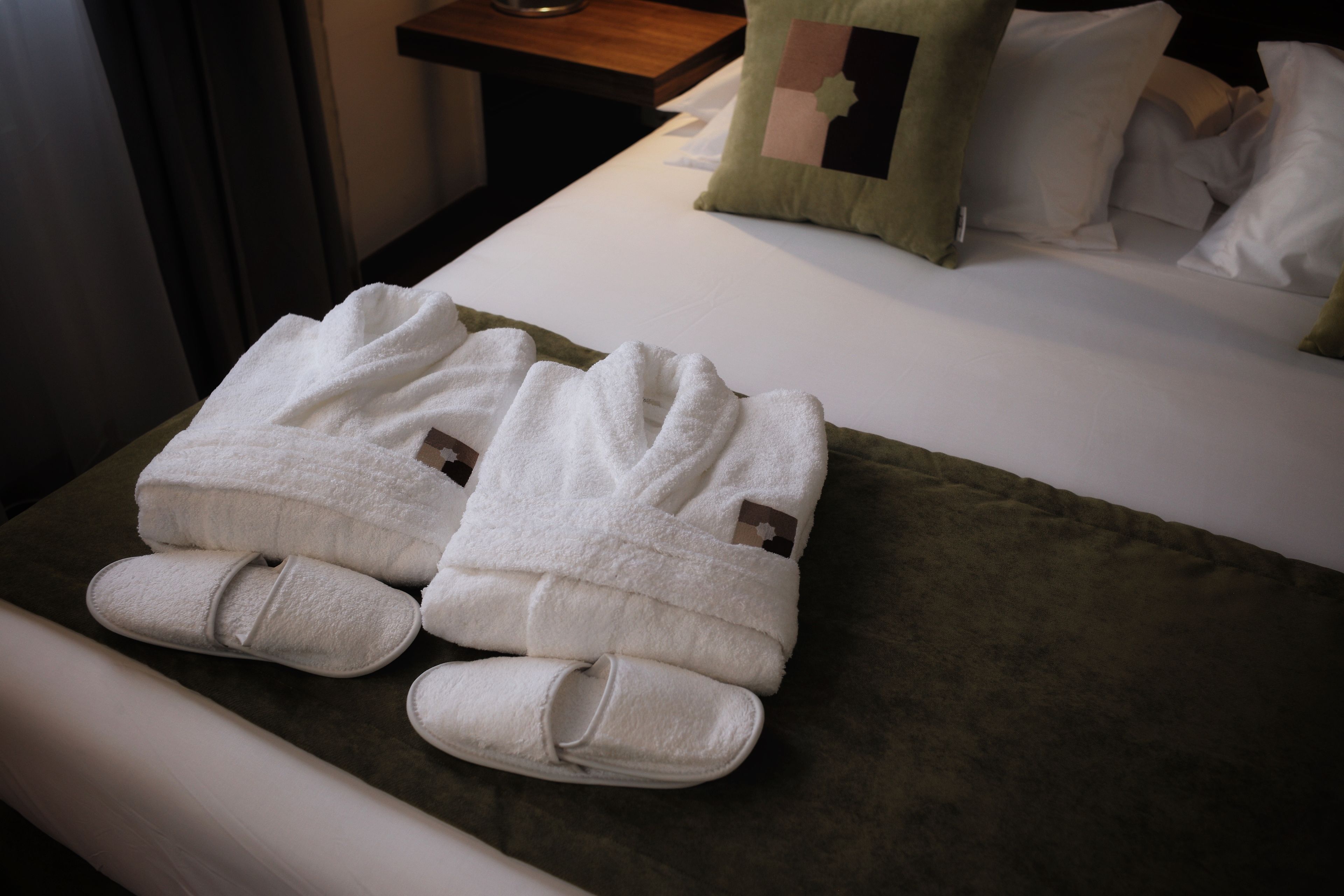 A neatly made bed with white linens and a green pillow.