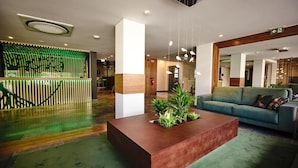A modern lobby with a reception desk, a green plant centerpiece, and a blue sofa. - Hotel Cruzeiro (Angra do Heroismo)