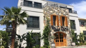 Un edificio moderno con facciata in pietra, ampie finestre e un balcone con decorazione a motivi alberi.