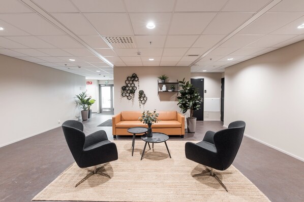 A modern lobby with a sofa, two armchairs, a coffee table, and potted plants. - Forenom Hotel & Apartments Vantaa Tikkurila (Vantaa)