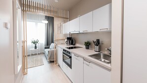 A modern kitchen with white cabinets, a stainless steel sink, and a built-in oven.