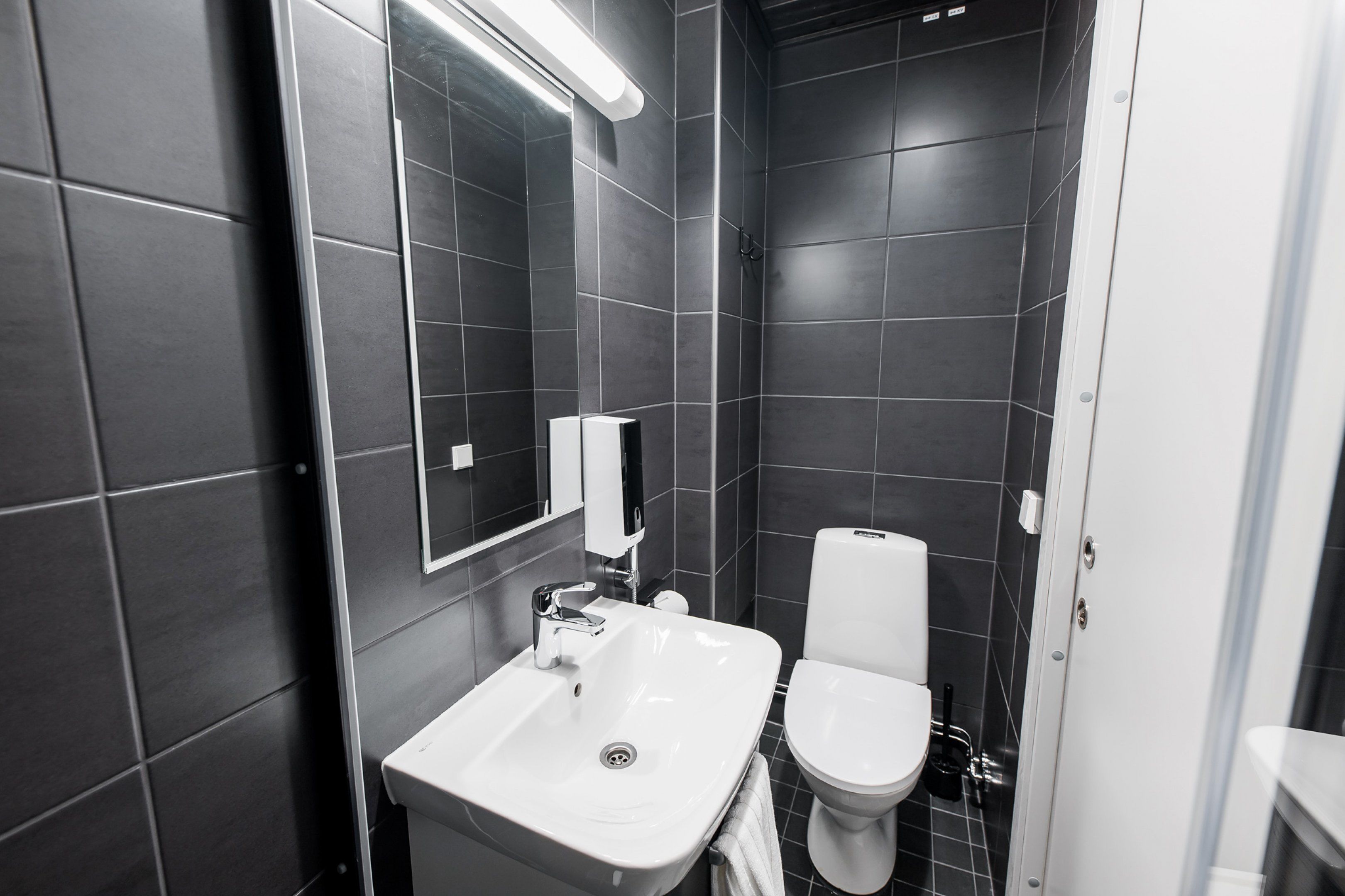 A modern bathroom with a white sink, a toilet, and a mirror.