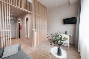 A modern living room with a sofa, a coffee table, a TV mounted on the wall, and a wooden partition. - Forenom Hotel & Apartments Vantaa Tikkurila (Vantaa)