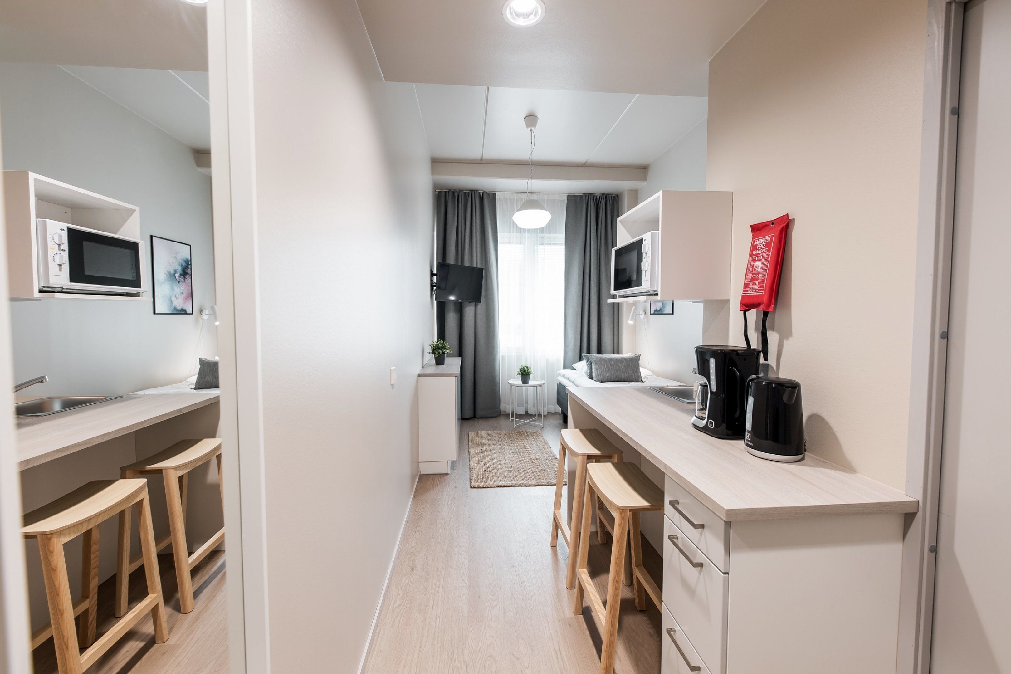 A modern kitchen with built-in appliances, wooden stools, and a coffee station.