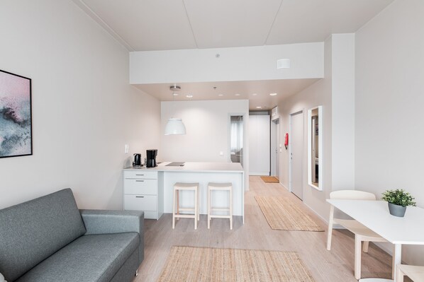 Una cocina moderna con armarios blancos, una isla central con taburetes y un comedor con mesa y sillas.
