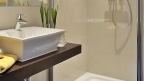 Une salle de bain moderne avec un lavabo blanc, un miroir et une douche.