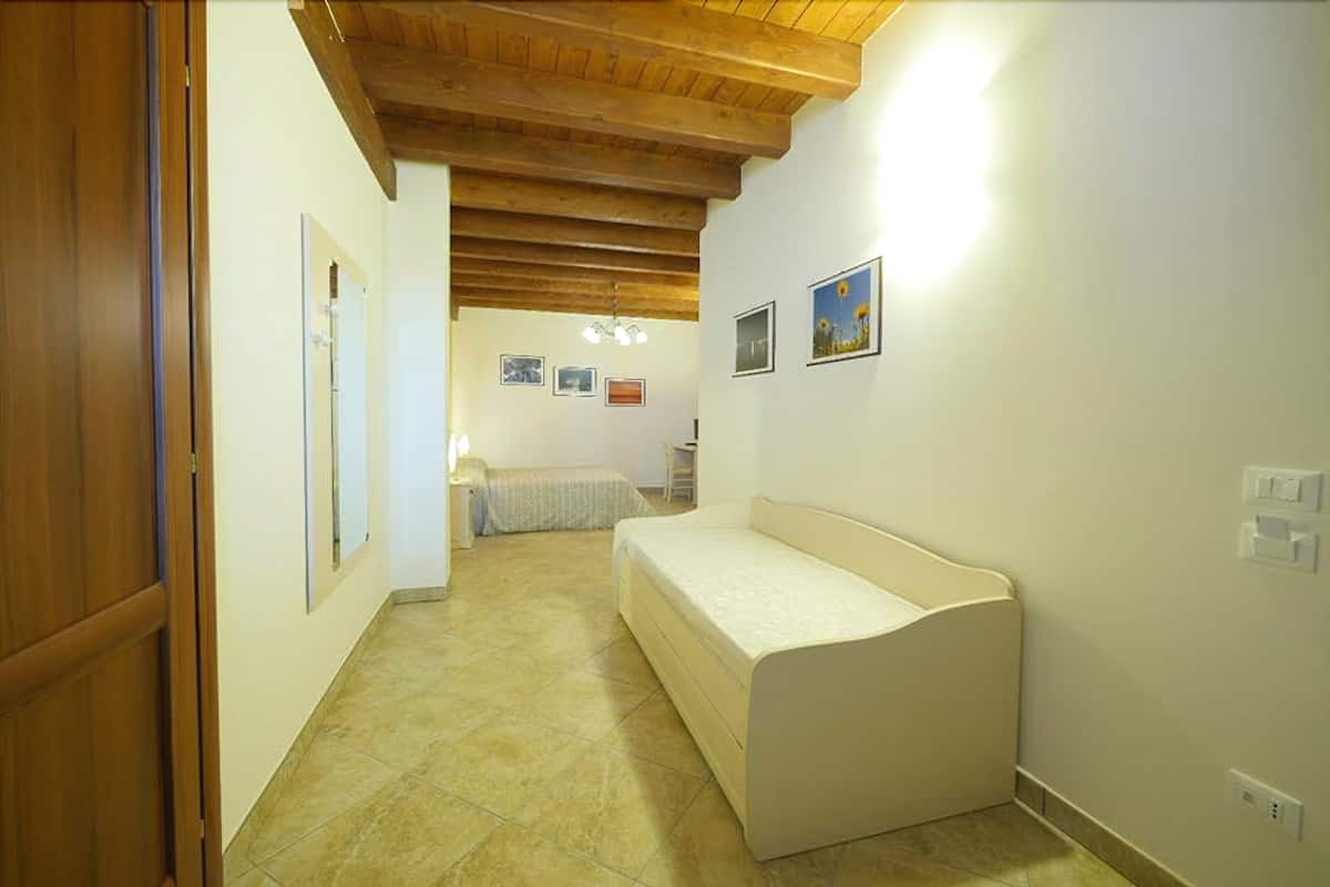A narrow hallway with a wooden ceiling and a bed in the distance.