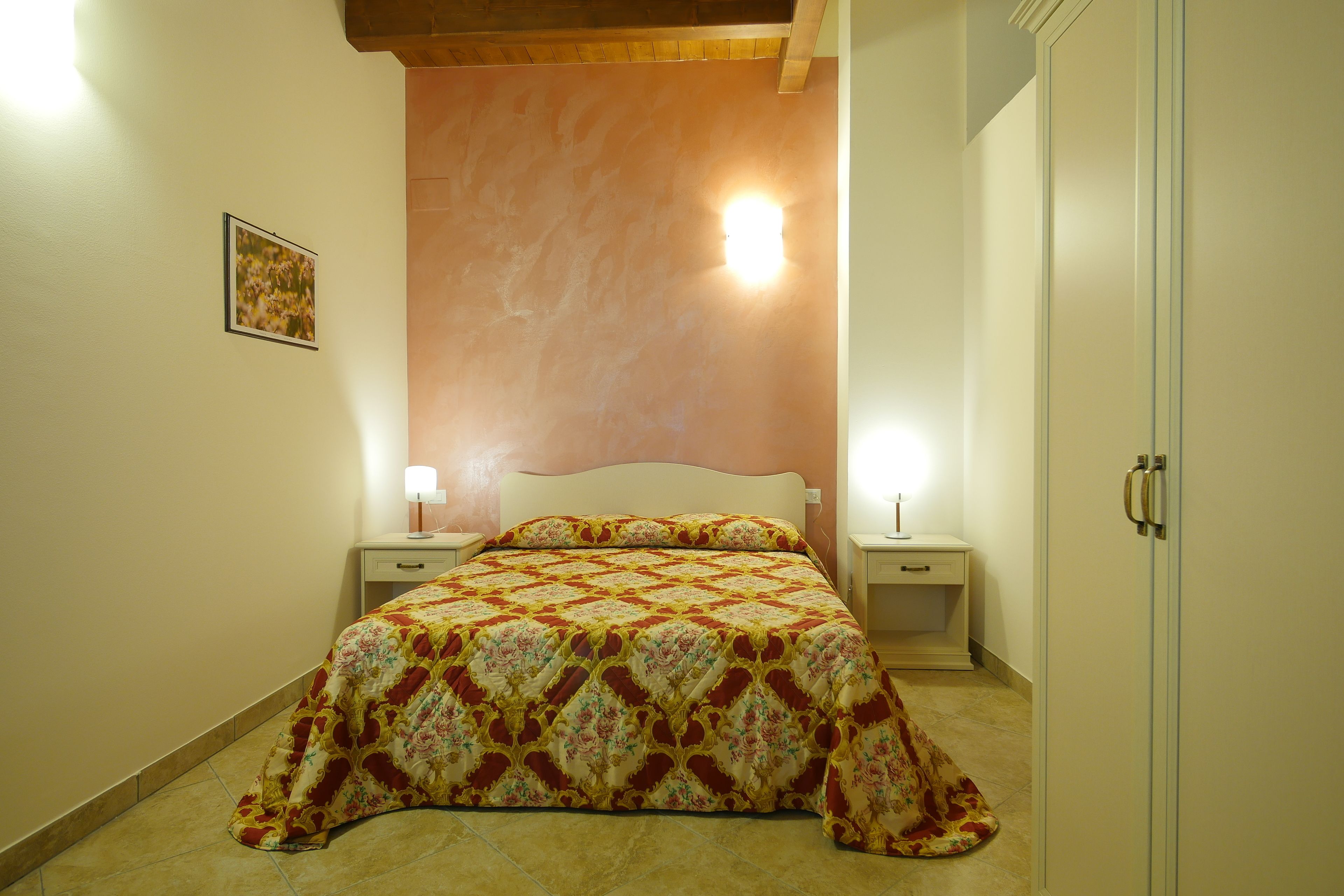 Une chambre à coucher comprenant un lit, des tables de chevet, une armoire et un luminaire fixé au mur.