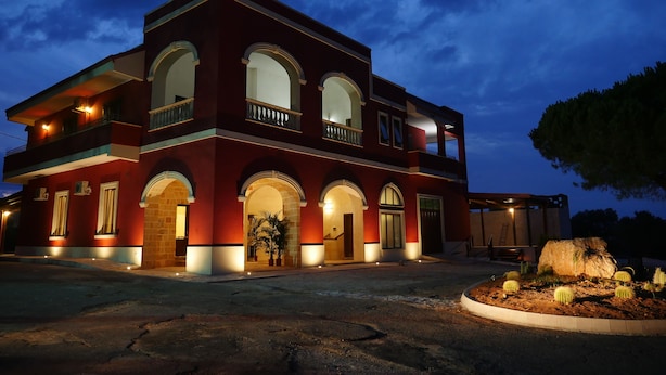 A two-story building with arched windows and a balcony, surrounded by a landscaped garden with cacti. - Tenuta Cavalieri (Leverano)