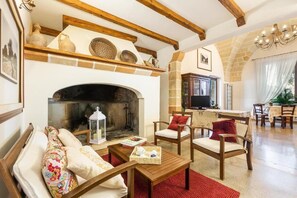 A cozy living room with a fireplace, wooden furniture, and stone walls. - Tenuta Cavalieri (Leverano)