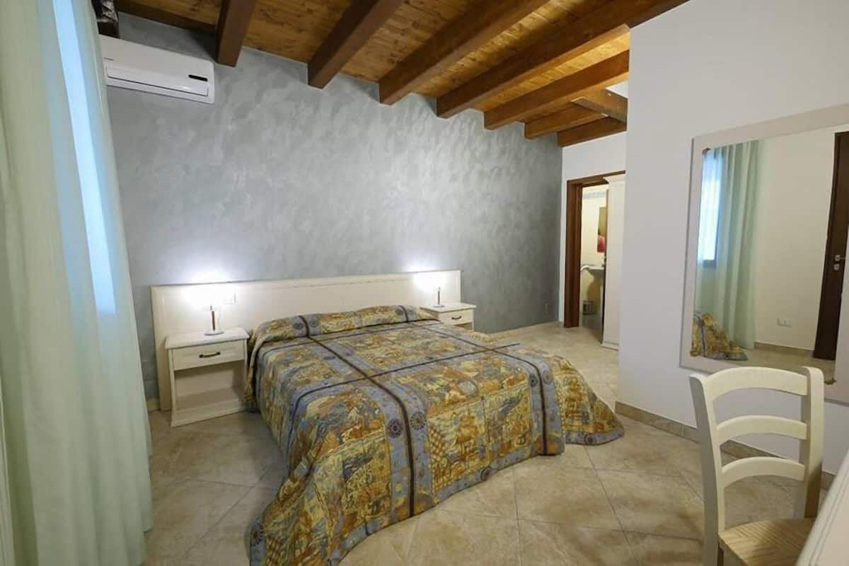 A bedroom with a bed, bedside tables, a chair, and a mirror.