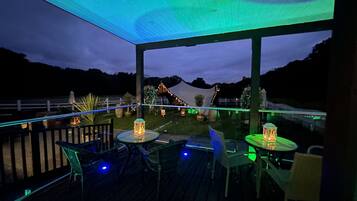 An outdoor patio with tables and chairs, a covered area, and a view of the surrounding landscape.