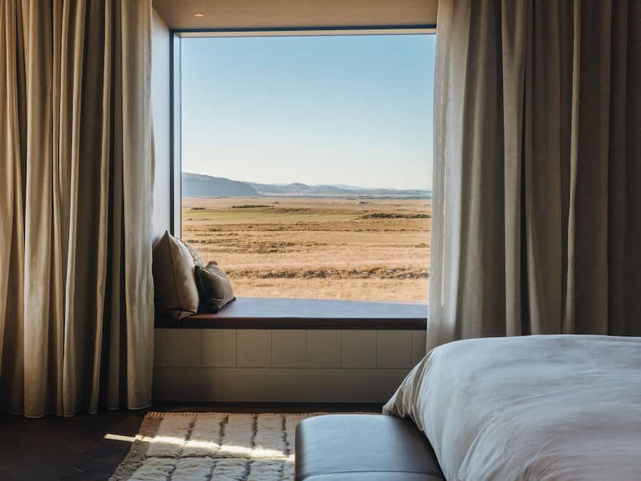 Un dormitorio con un ventanal grande, una cama y vistas al paisaje.