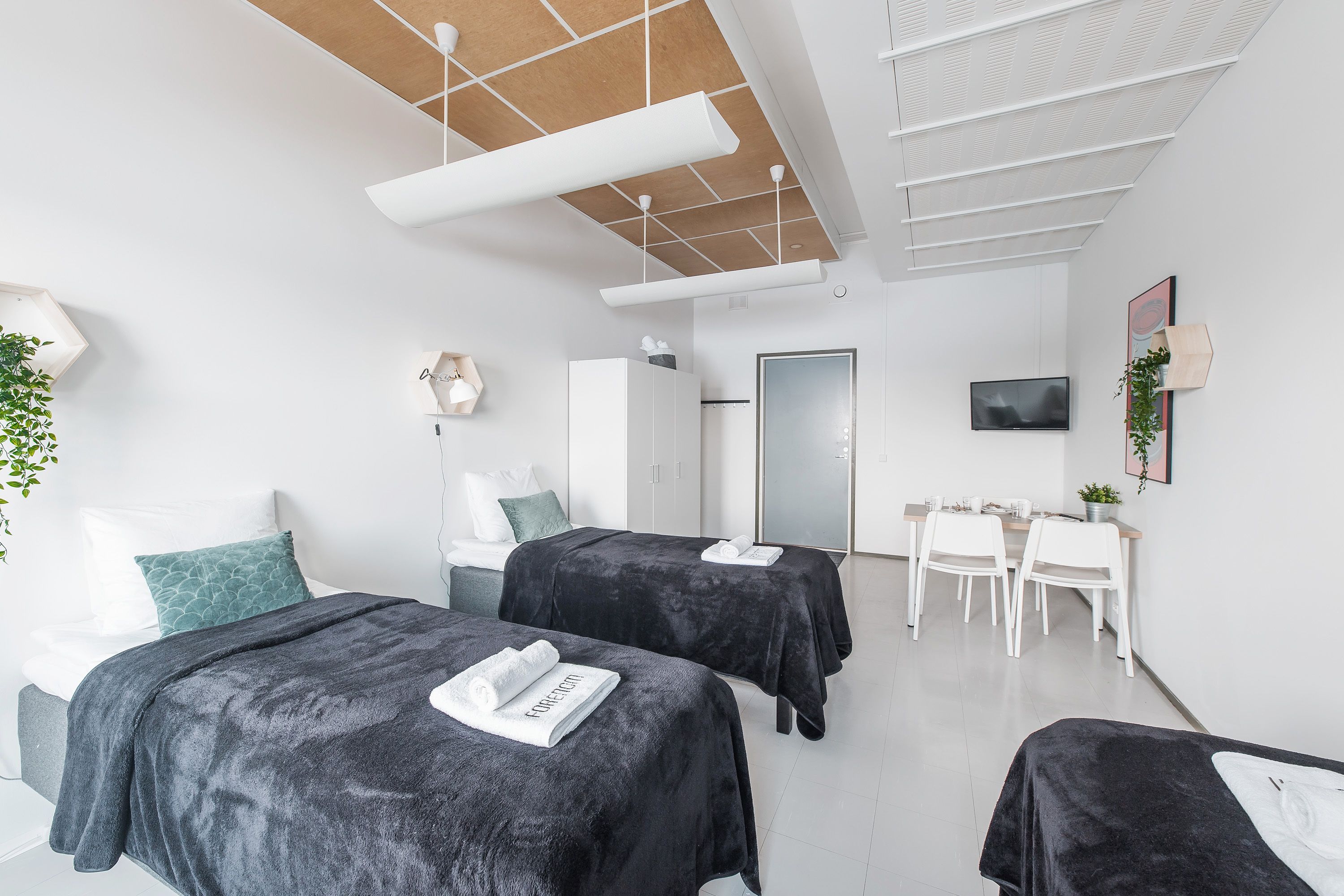 Moderni hotellihuone, jossa on kaksi sänkyä, työpöytä ja televisio.