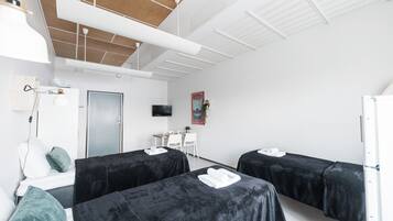 A modern hotel room with two beds, a desk, a TV, and a door.