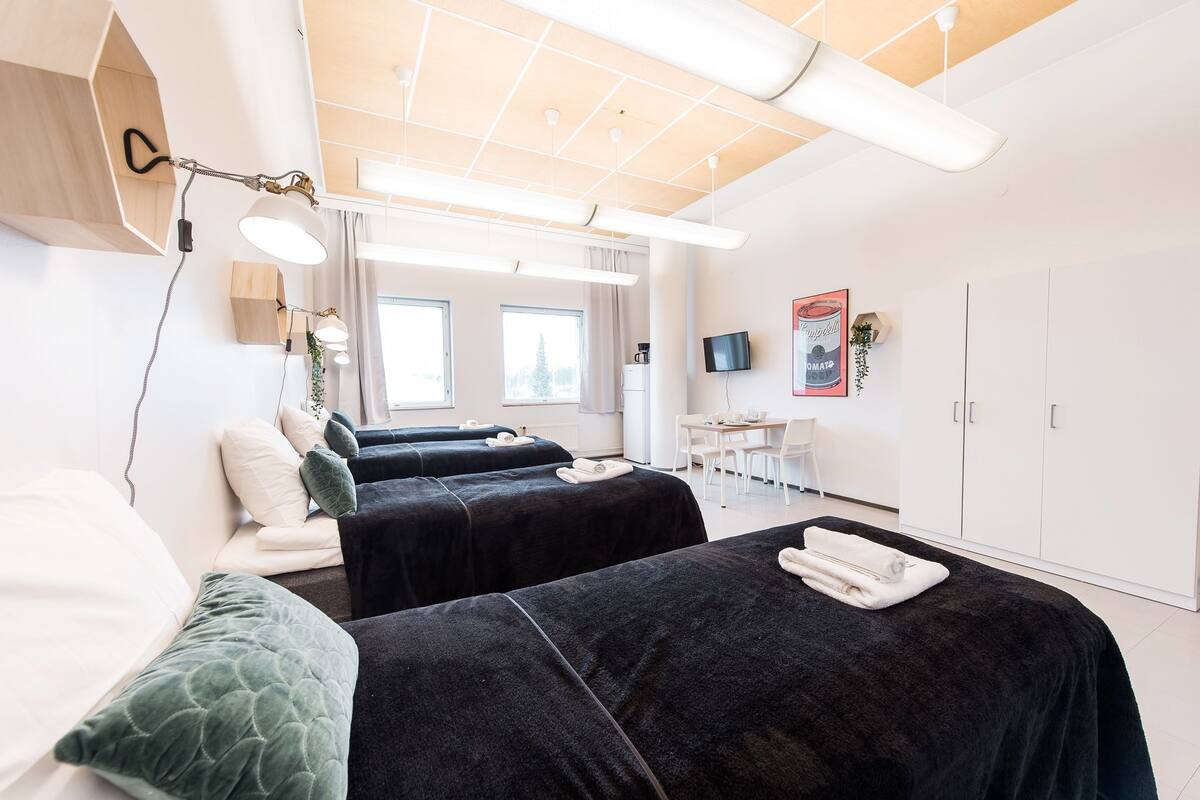 A modern hotel room with two beds, a desk, and a television.