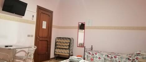 A room with a bed, a chair, a desk, and a television.