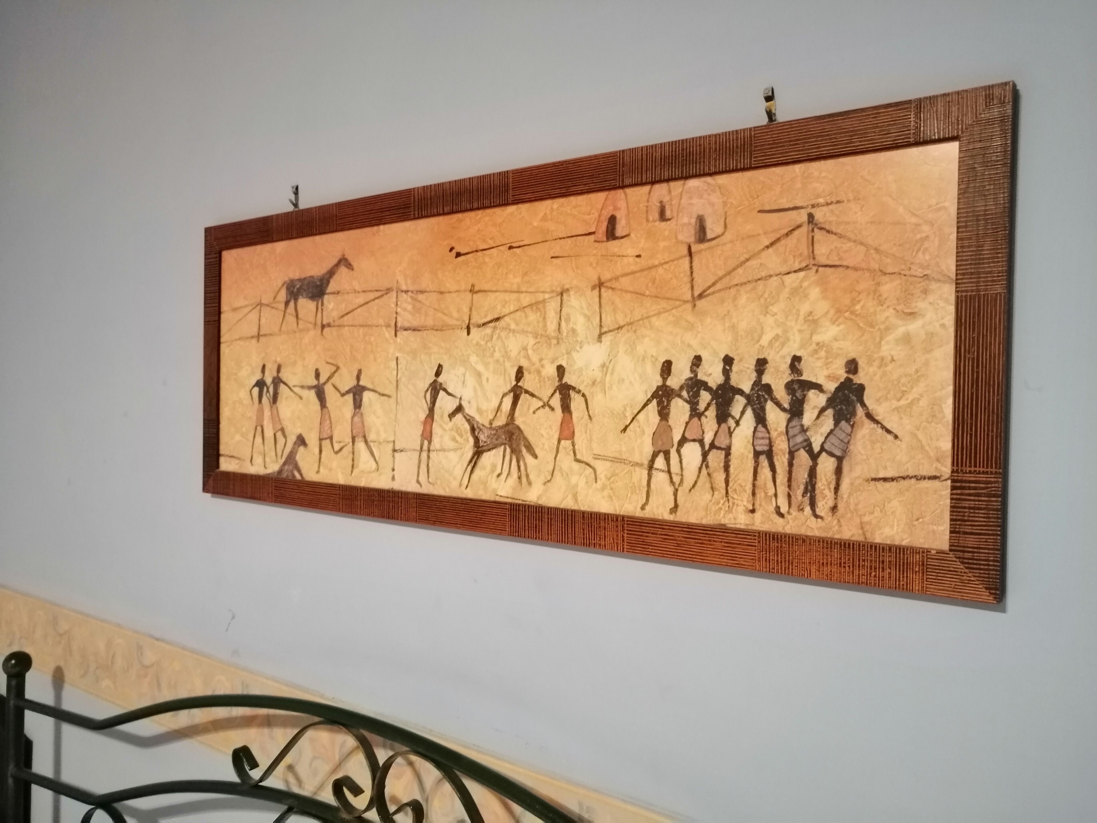 Un cuadro colgado en la pared que muestra una escena prehistórica con figuras y animales.