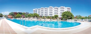 A large swimming pool with lounge chairs and umbrellas, surrounded by a white building with balconies. - Olbios Marina Resort (Erdemli)