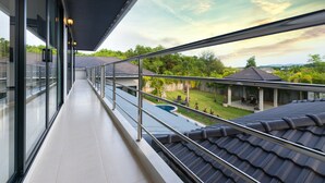 A balcony with a view of a swimming pool and a covered patio area. - Grand Villa Luxury Holidays Phuket (Choeng Thale)