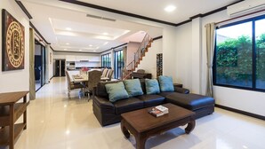 A modern living room with a sofa, coffee table, and a staircase leading to an upper level. - Grand Villa Luxury Holidays Phuket (Choeng Thale)