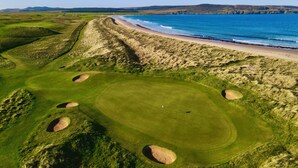 Un parcours de golf avec des bunkers, une plage et une vue sur l’océan.