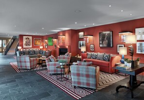 Un salon spacieux avec un mur rouge, une cheminée et un escalier menant à l’étage supérieur.