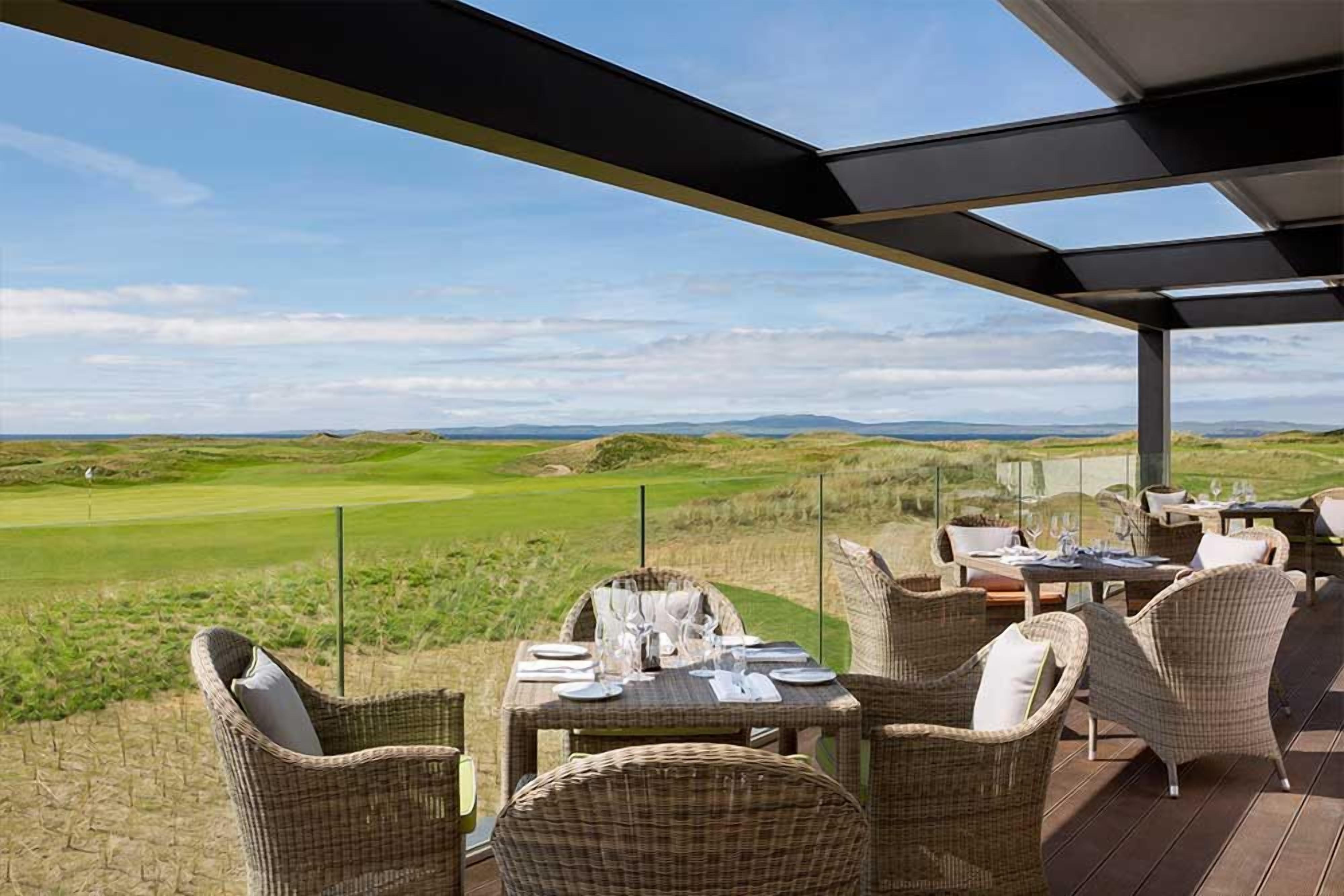 An outdoor dining area with wicker furniture and a view of a golf course.