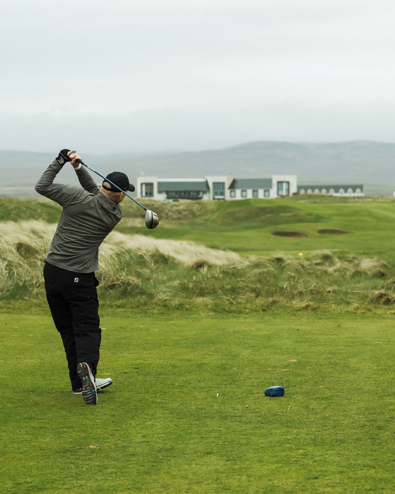 A person playing golf on a course with a building in the background.