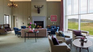Un salon spacieux doté d’une cheminée, de sièges confortables et de grandes fenêtres offrant une vue sur l’extérieur.
