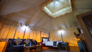 A tented accommodation with a bed, sofa, and a table with a lamp. - Three Hills Resort & Spa, Coorg (Madikeri)