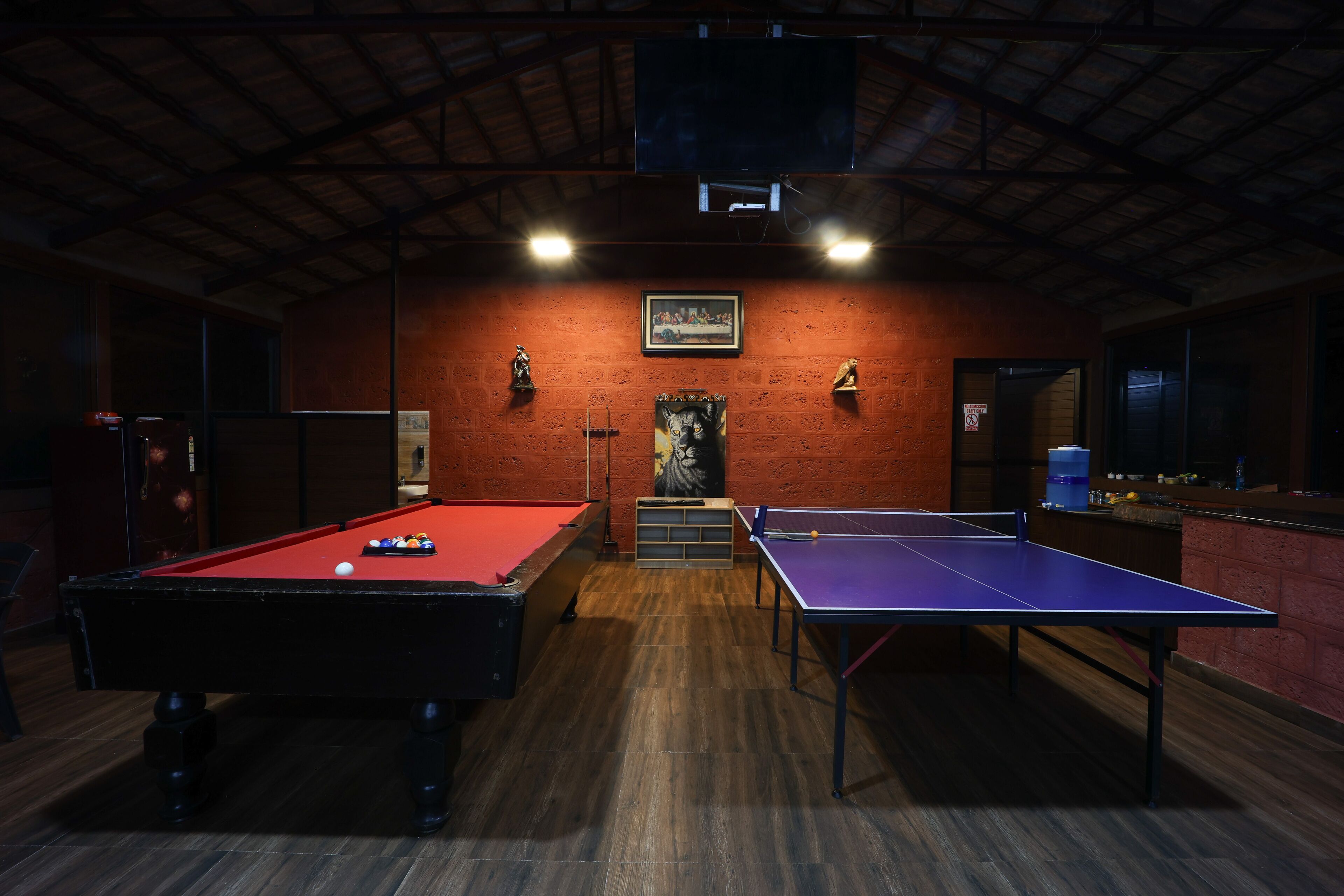 Una sala de billar con dos mesas de pool, una roja y otra azul.