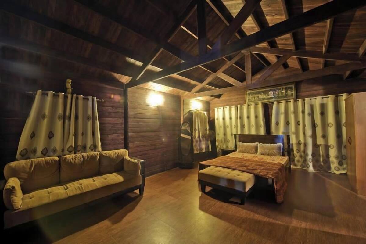 Una habitación con techo de madera, una cama, un sofá y cortinas.