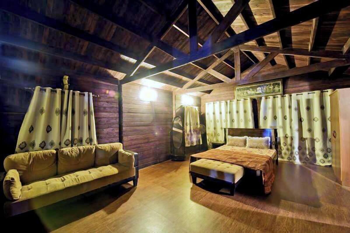 Una habitación con techo de madera, una cama, un sofá y cortinas.