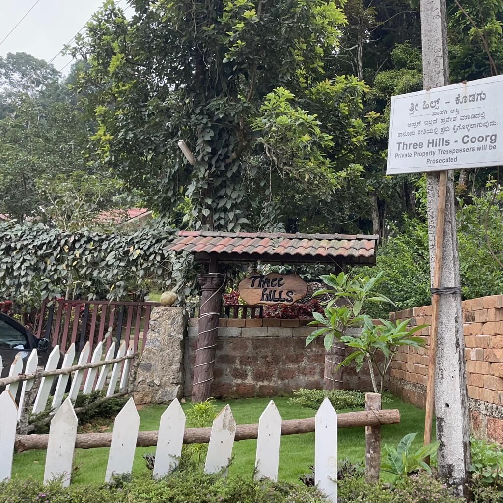 Un letrero que dice "Three Hills - Coorg" con una advertencia sobre intrusos.