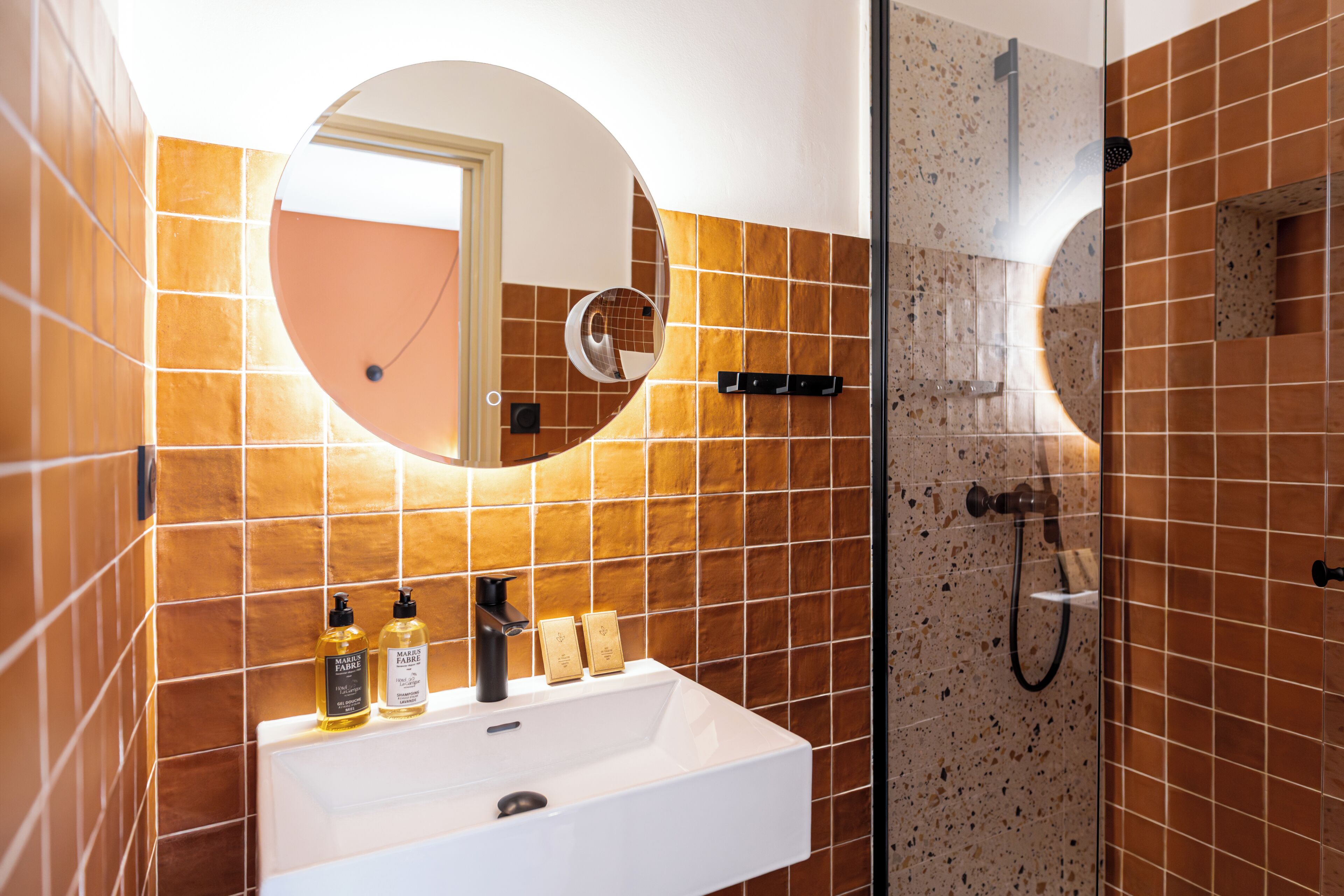 A bathroom with a white sink, mirror, and shower.