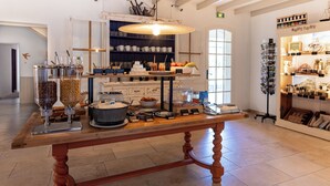 A café with a wooden table displaying various food items and a coffee station.